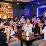 Enjoying 제주도유흥 in a lively room salon atmosphere with friends, neon lights and whiskey.